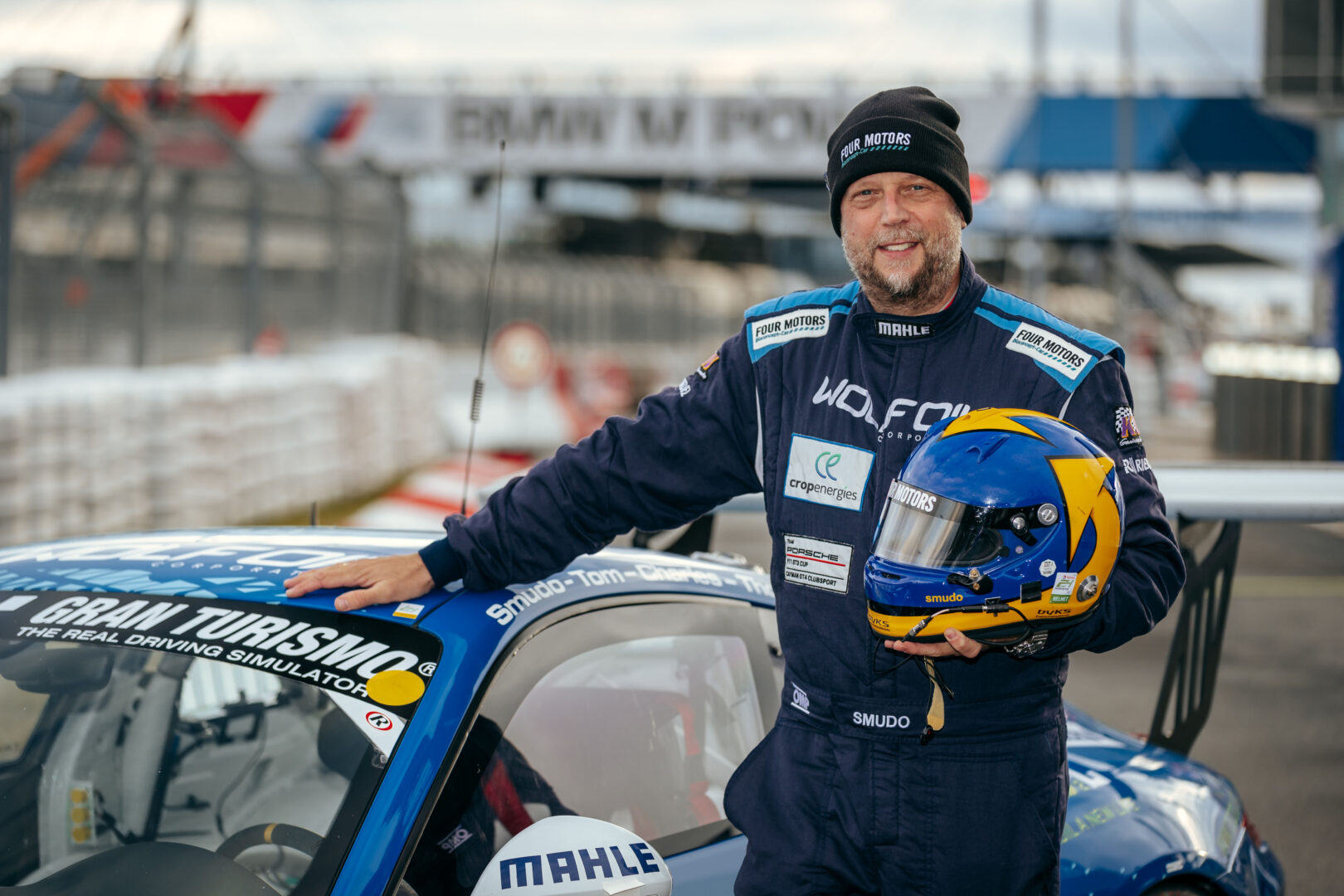 Der Rapper und Rennfahrer Smudo neben einem Porsche-Rennauto des Teams Four Motors.