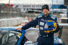 Der Rapper und Rennfahrer Smudo neben einem Porsche-Rennauto des Teams Four Motors.